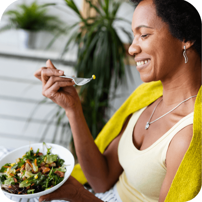 A woman eating a salad. House plants in the background.